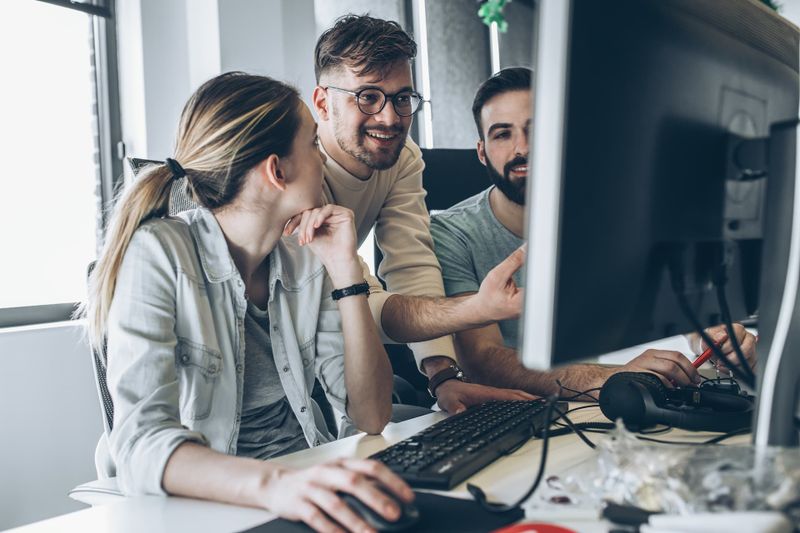 Three professionals reviewing documents on a computer.