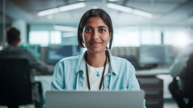 Student looking into camera while working on laptop.