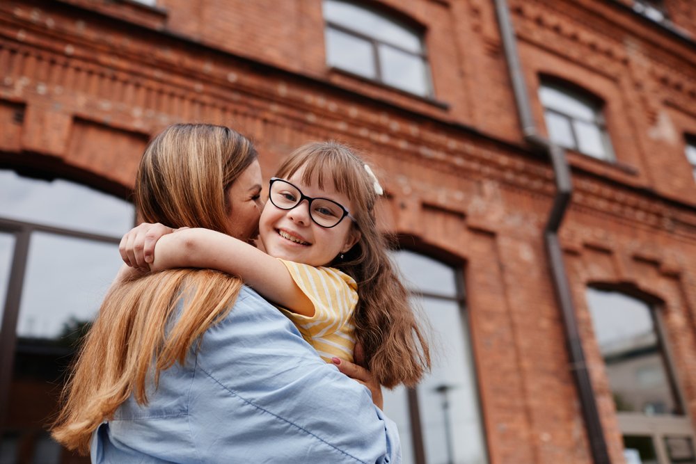 Young child embracing mother outdoors.
