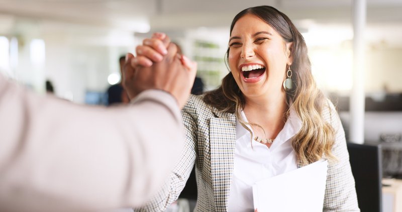 Coworkers high-fiving in office.