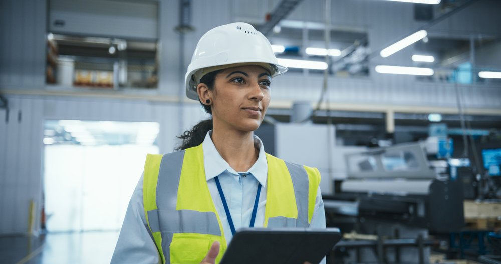 Safety professional holding tablet in industrial workplace.