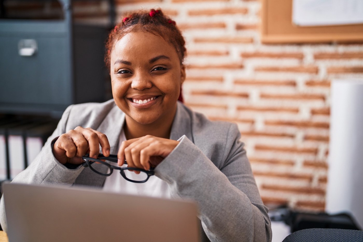 Person holding glasses while sitting in home office.