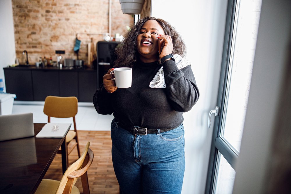 Person holding coffee mug talks on phone.