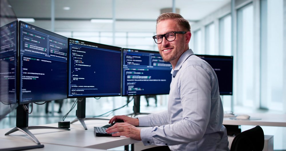 Programmer works on multiple computer screens.