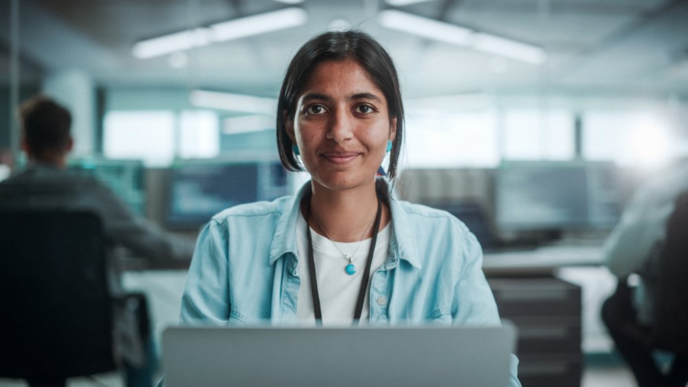 Student looking into camera while working on laptop.