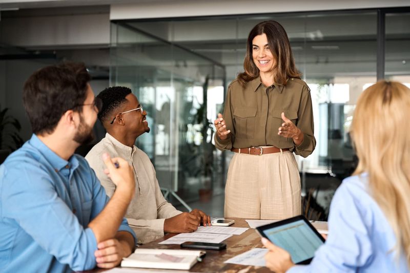 People working in a boardroom together with one person standing up at the front of the room.