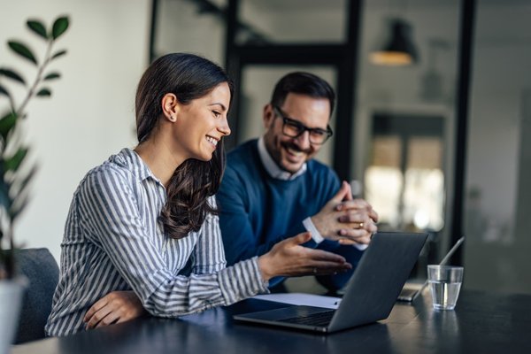 Two professionals working at a laptop together.